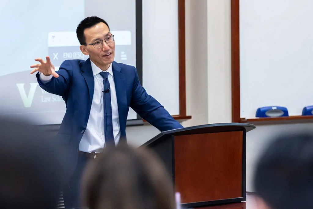A faculty member teaching a Law and Business class from a lectern